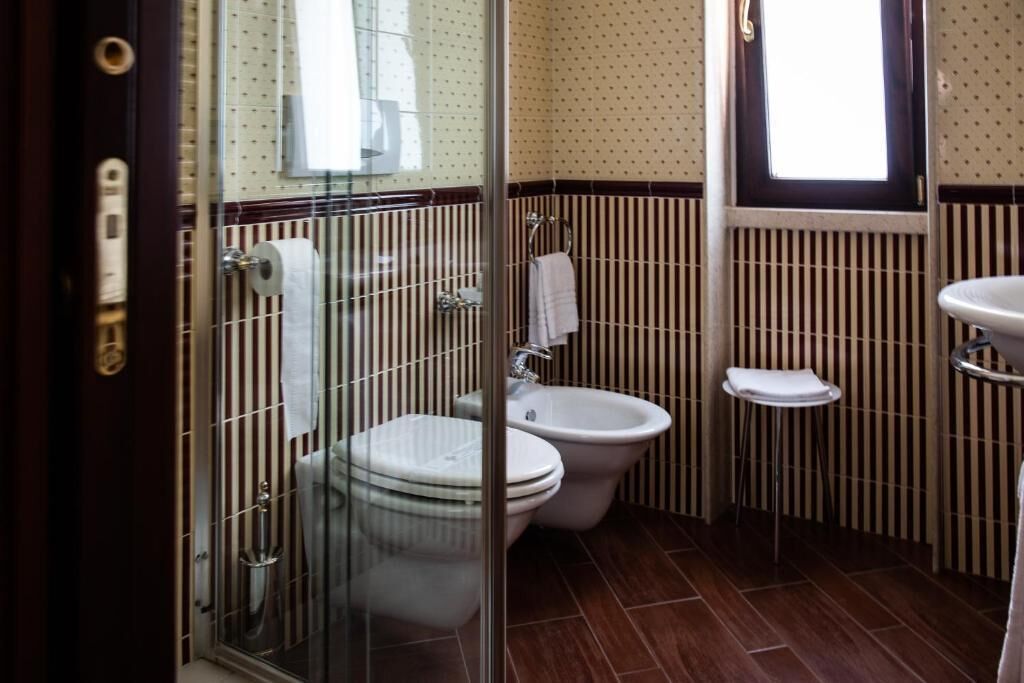 A bathroom with a glass shower enclosure, a toilet, a bidet, and a sink.