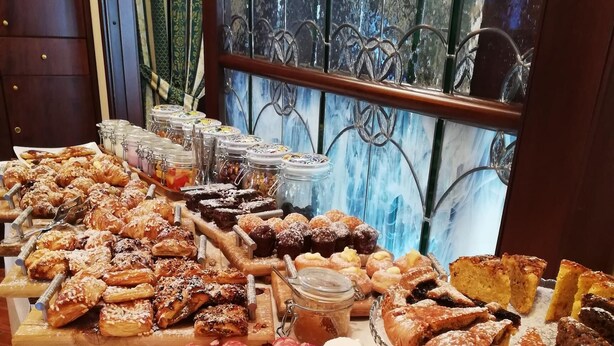 Un bufé con diversos pasteles, panes y embutidos.