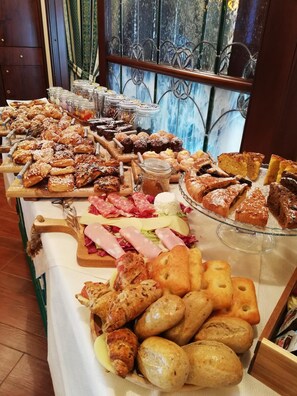 Un bufé con diversos pasteles, panes y embutidos.