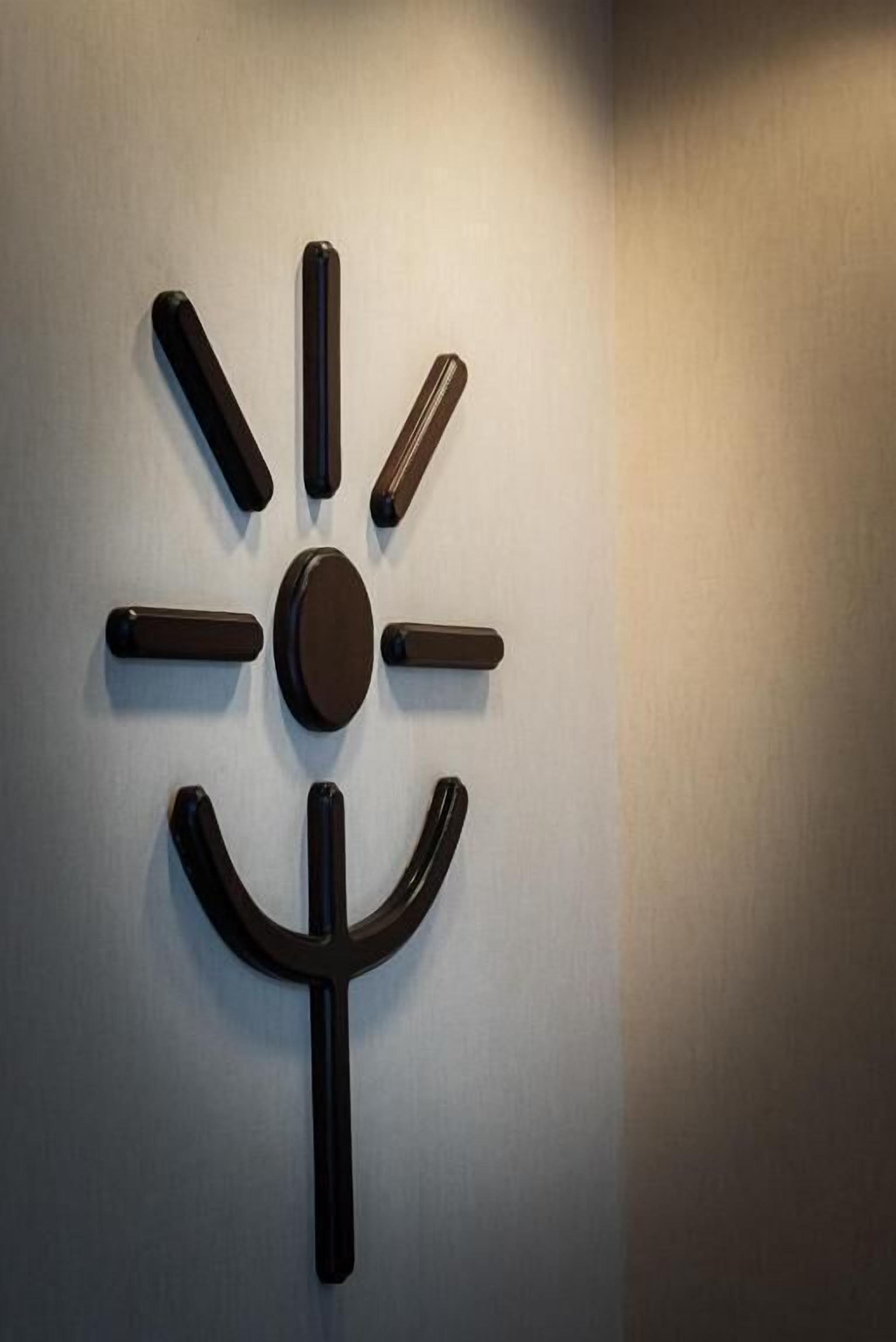 Una obra de arte abstracta montada en la pared, con un elemento circular central y extensiones simétricas.