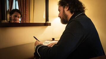 Una persona sentada en un escritorio, escribiendo en un cuaderno con una lámpara.