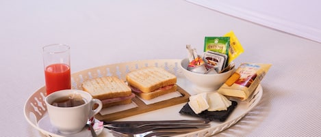 A tray with sandwiches, cheese, a glass of juice, and condiments on a table.