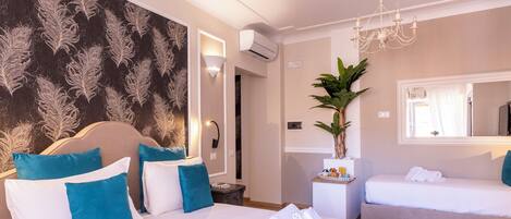 A hotel room with a large bed, a smaller bed, a potted plant, and a mirror.