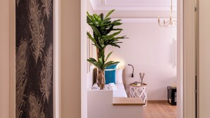A modern hotel room with a bed, a small side table, a plant, and a chandelier. - Trastevere Paper Suites (Rome)
