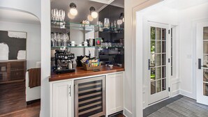 Une cuisine équipée d’une machine à café, de verres et d’un panier de collations.