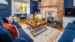 Un salon avec un canapé bleu, une table basse en bois, une cheminée et un téléviseur.