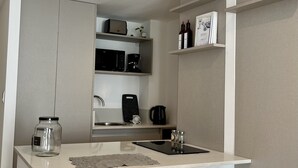 A compact kitchen with a central island, white bar stools, and a microwave above the sink. - Luxury Studio in San Telmo (Buenos Aires)