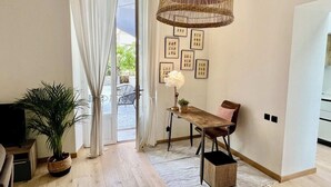 Ein Zimmer mit Holzboden, einem Esstisch mit Stühlen, einer hängenden Korbtreppe, einer Topfpflanze und einer Wand mit gerahmten Bildern.