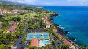En semesteranläggning vid kusten med tennisbana, pool och utsikt över havet.