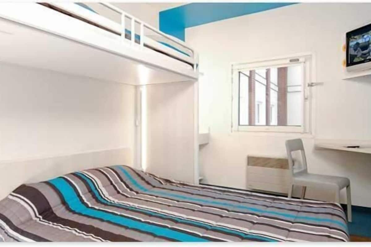 Habitación con literas, un escritorio, una silla, una ventana y un televisor.