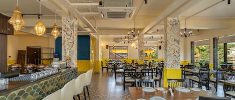Un restaurante espacioso con techos altos, baldosas de suelo con diseños y diversas opciones de asientos, incluidas mesas y sillas.