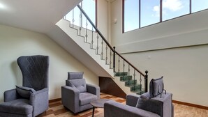 A spacious living area with a modern staircase, grey upholstered furniture, and a wooden floor. -  La Baga Beach Hotel (Calangute)