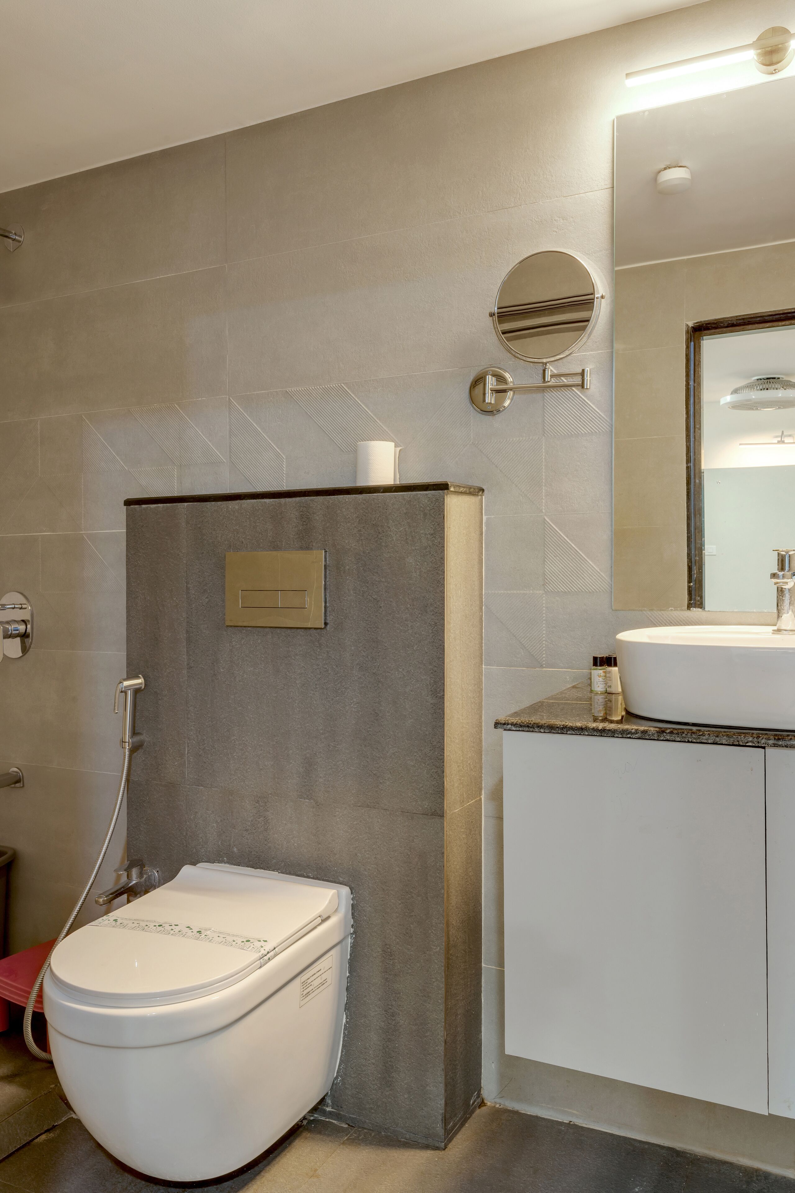A modern bathroom with a toilet, sink, and mirror.