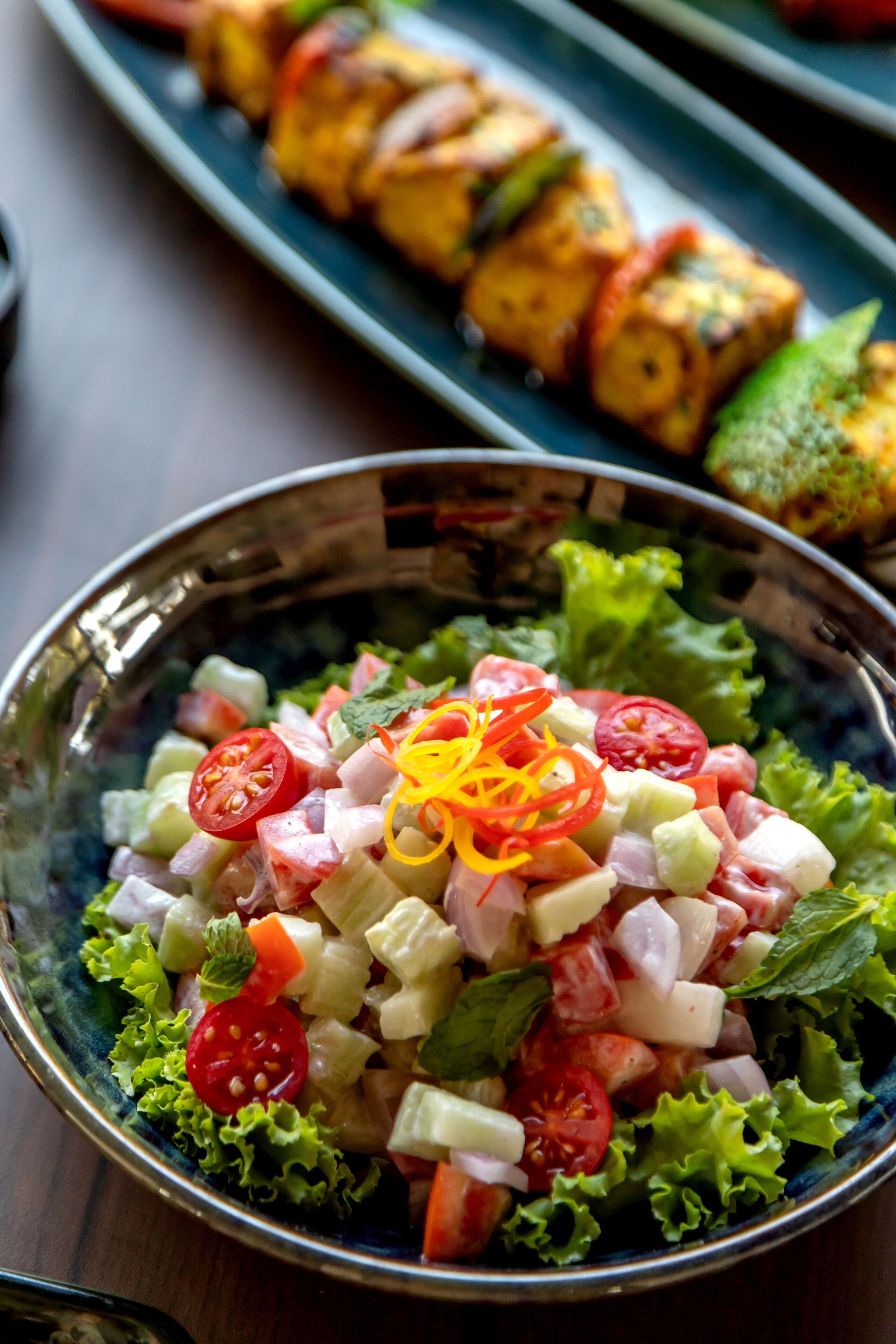 A bowl of salad with various vegetables and a decorative garnish.
