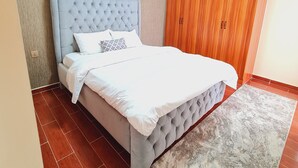 Una camera da letto con un letto e una testiera capitonné, un armadio in legno e un tappeto decorato.