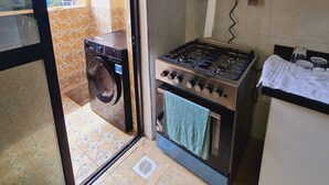Una cucina funzionale con piano cottura a gas, lavatrice e scaldabagno.