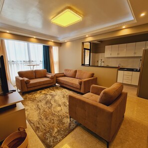 A modern living room with a sectional sofa, a flat-screen TV, and a large window with curtains.