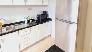 Una cucina moderna con mobili bianchi, un frigorifero in acciaio inossidabile, un piano di lavoro nero e un lavello con rubinetto.