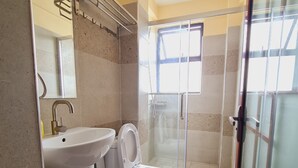 Un bagno con lavandino, WC e cabina doccia in vetro.