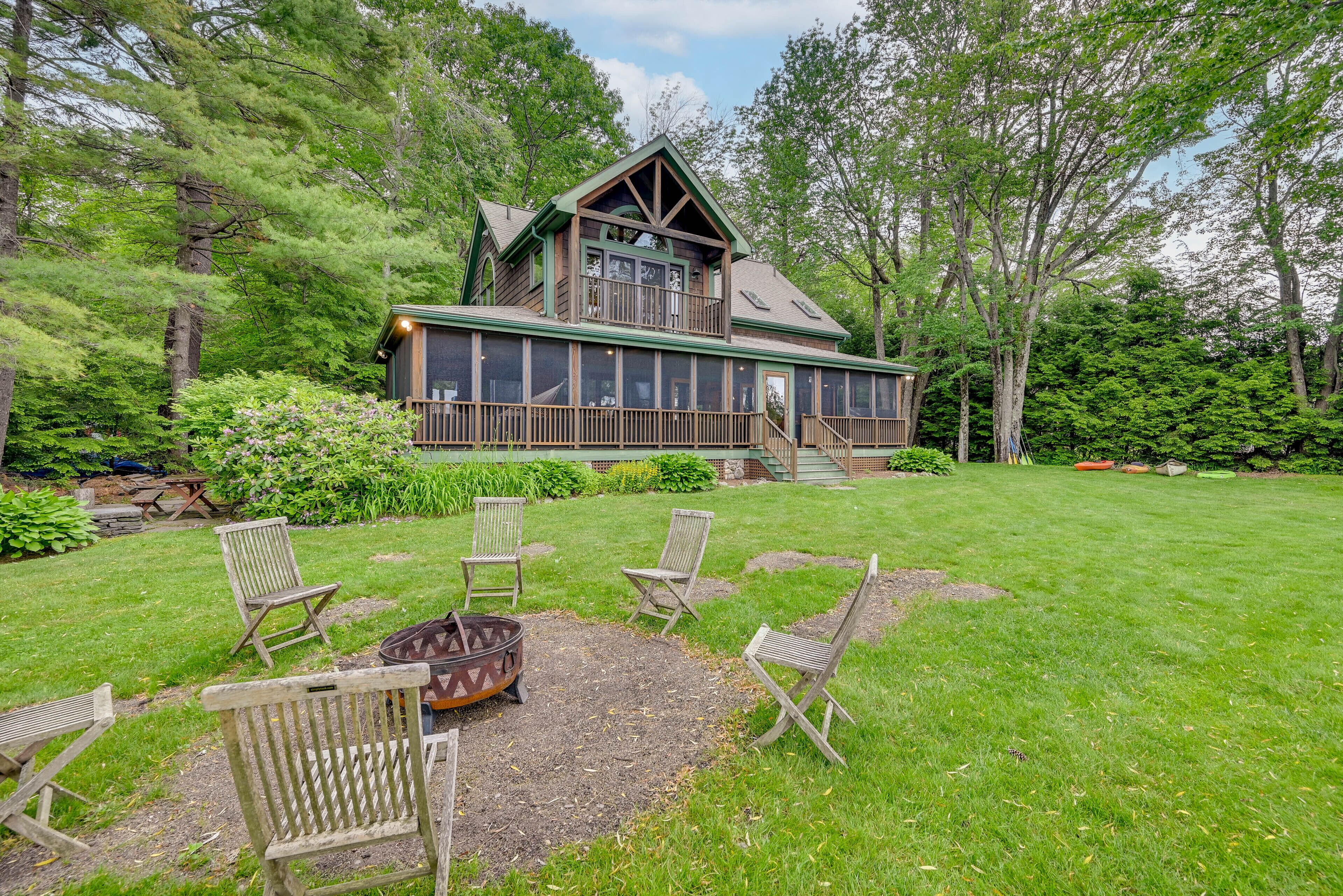 A lodge with a large deck, outdoor seating, and a fire pit.
