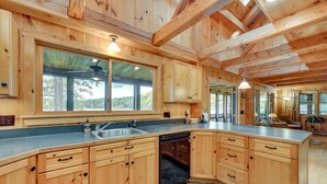A spacious kitchen with wooden cabinets, a dishwasher, and a large window offering a view of the outdoors. - Lakefront Westhampton Cabin w/ Beach + Kayaks! (Westhampton)