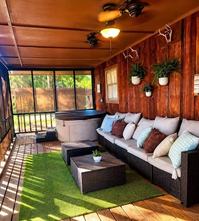 A covered patio with a sofa, a hot tub, and potted plants.. The Gator Den at Caddo Lake / Big Lake