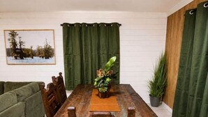 Una mesa de comedor de madera con bancos, un centro de mesa con planta verde y un cuadro en la pared.