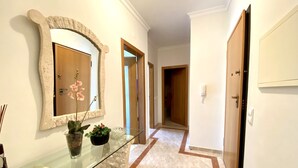 A hallway with a glass display case, a mirror, and a door leading to another room. - VILAMOURA TYPICAL 2 WITH POOL by HOMING (Vilamoura)