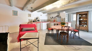 A compact living space with a dining area, kitchenette, and a cozy seating area with a red sofa and a small table.