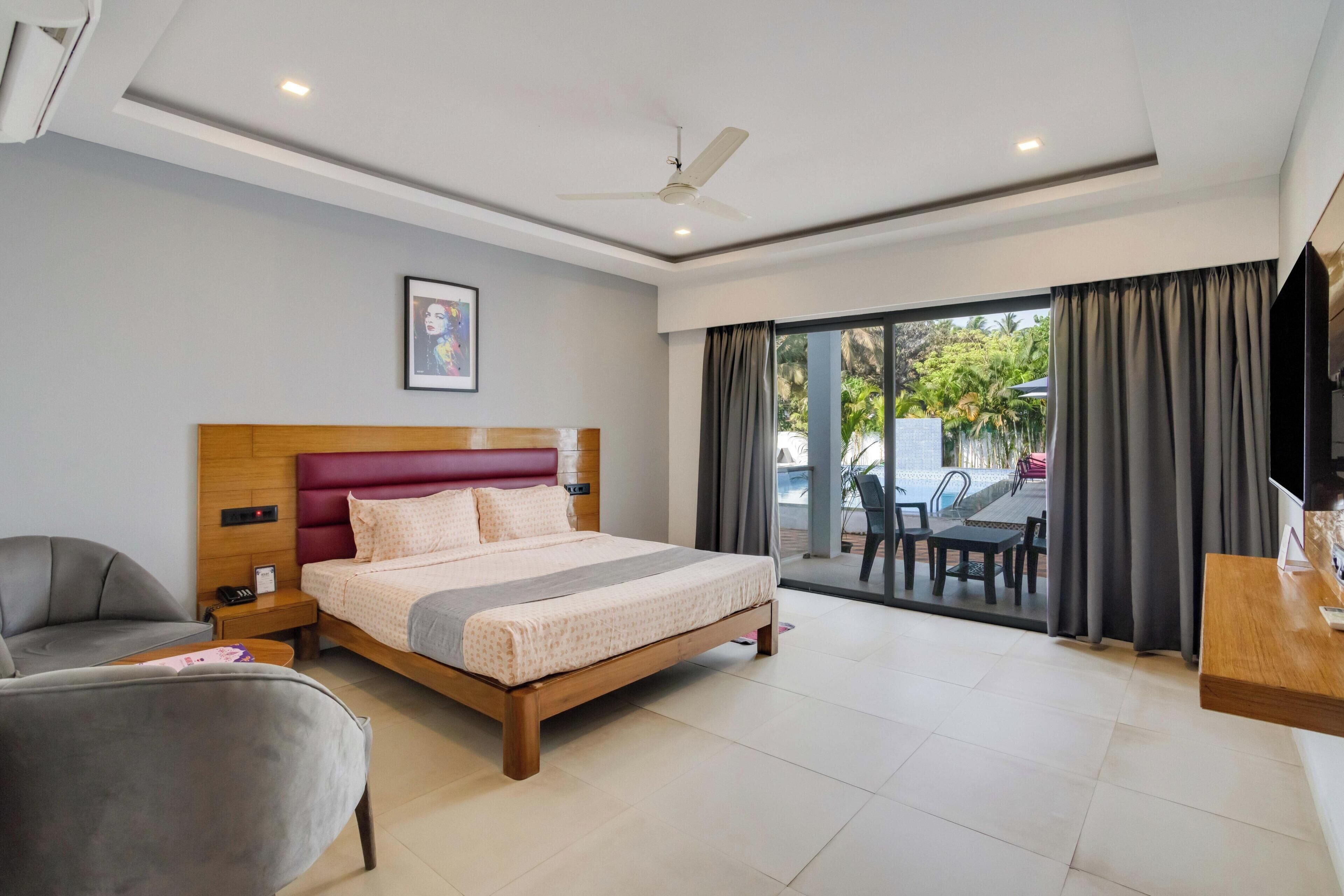 A modern hotel room with a bed, a desk, a chair, and a view of the outdoors.