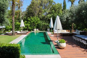 Una piscina al aire libre, sombrillas, sillones reclinables de piscina