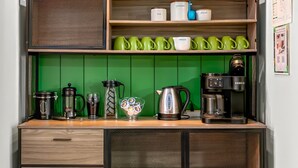 Una encimera de cocina con equipo para preparar café, incluyendo una máquina Keurig, una cafetera y una prensa francesa.