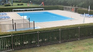 Una piscina con muelle cercado, sillas de descanso y un flotador salvavidas.
