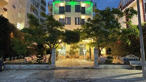 Un hotel con un letrero que dice "SANREMO" en la parte superior, rodeado de árboles y un área de entrada pavimentada.