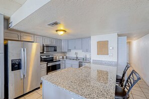 A modern kitchen with granite countertops, stainless steel appliances, and light gray cabinetry.