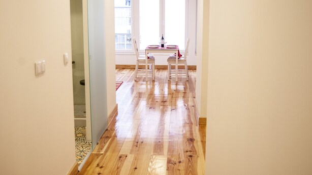 A hallway with wooden flooring leading to a dining area with a table and chairs. - Apartamento / Estudio no Centro de Lisboa Para Casal ou Família (Lisboa)