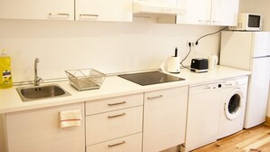 A modern kitchen with a sink, dishwasher, microwave, and a washing machine. - Apartamento / Estudio no Centro de Lisboa Para Casal ou Família (Lisboa)
