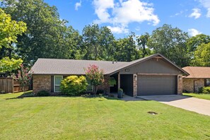 A single-story house with a garage, a brick exterior, and a well-maintained lawn.