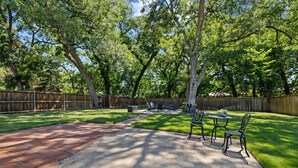 Un jardin avec une terrasse, une clôture en bois et une pelouse.