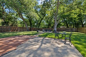 Ein Garten mit Terrasse, Holzzaun und Rasenfläche.