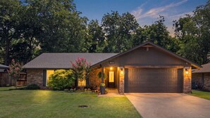 Une maison d’habitation avec un garage, une pelouse bien entretenue et une façade en briques.