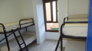A dormitory room with bunk beds, a window, and a door. - Albergue Roma (Lena)