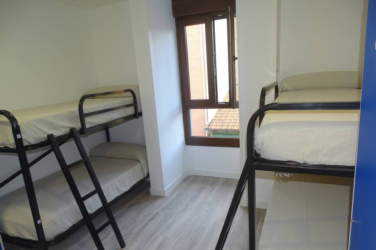 Un dormitorio con literas, una ventana y una puerta.