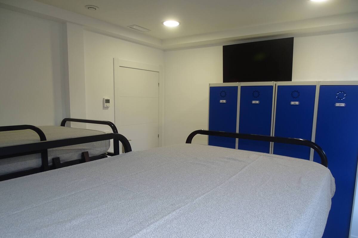 Un dormitorio con literas, un televisor y taquillas azules.