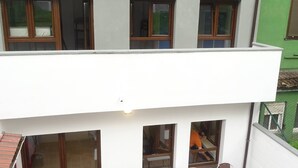 A multi-story building with a terrace featuring outdoor seating and a view of the surrounding area. - Albergue Roma (Lena)
