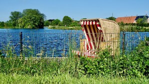 A riverside view with a wicker chair and a fence. - Stadtnah, Eigener Garten, Ruhig (Emden)