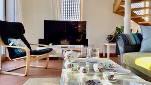 A living room with a TV, a sofa, a chair, and a table set with tea ware. - Stadtnah, Eigener Garten, Ruhig (Emden)