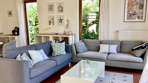 A living room with two grey sofas, a white coffee table, and a bookshelf. - Stadtnah, Eigener Garten, Ruhig (Emden)