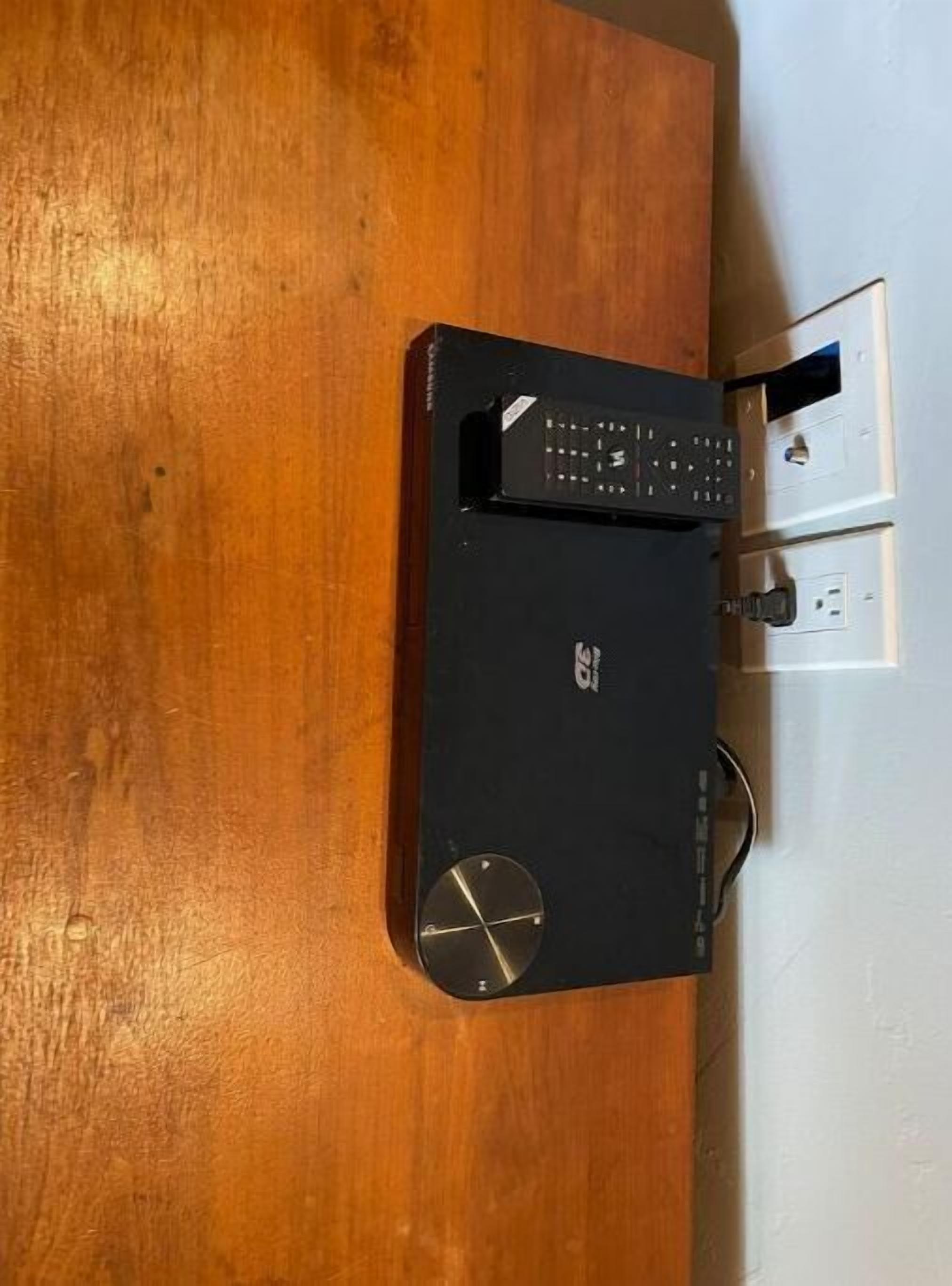 En sort elektronisk enhed med et tastatur og en lille skærm på en træoverflade.