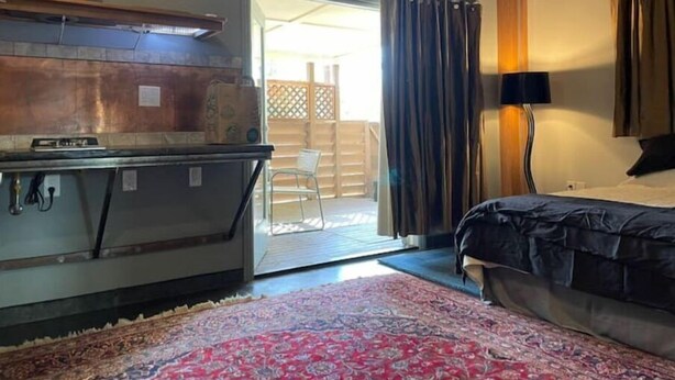 A room with a bed, a desk, a chair, and a large window with curtains. - Unique studio with cozy patio (La Mesa)